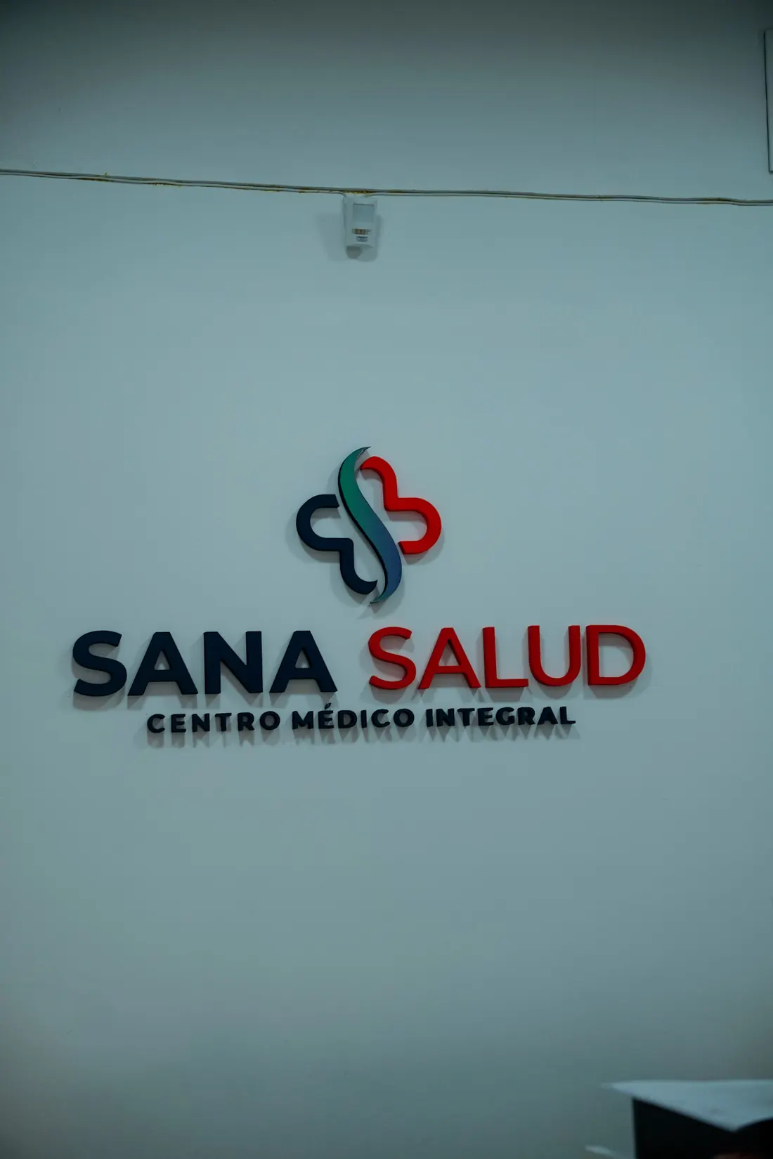Logo corpóreo de Sana Salud, centro médico integral, en la pared de la recepción.